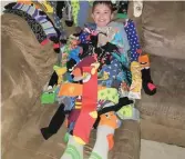  ??  ?? Got socks? Easton Mengel, 9, shows off most of the 69 pairs of socks he has received since the Socks for Smiles campaign began a few months ago. Photo courtesy Britten Hepting