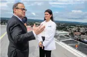  ?? AARON FLAUM Hartford Courant/TNS ?? Dr. Alan Friedman, Yale New Haven Hospital’s chief medical officer, talks with Evie Herman, 15, on the helipad at hospital as they wait for the SkyHealth helicopter on Aug. 28. Evie was granted a wish through Make-A-Wish to be an “oncologist for a day.”