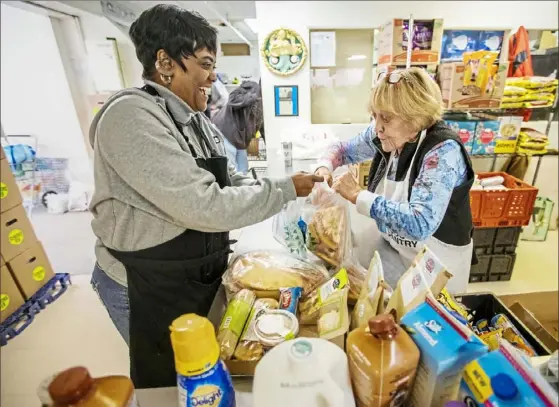  ?? Andrew Rush/Post-Gazette ?? Volunteers Goldie Rawlins, left, and D. Tolbert bag food at the Northside Common Ministries food pantry Tuesday on the North Side.