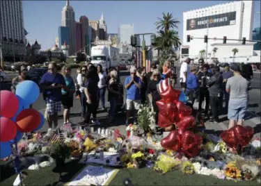  ?? JOHN LOCHER — THE ASSOCIATED PRESS ?? People pause at a memorial for the victims of a mass shooting in Las Vegas, Wednesday, Oct. 4, in Las Vegas. A gunman opened fire on an outdoor music concert on Sunday killing dozens and injuring hundreds.