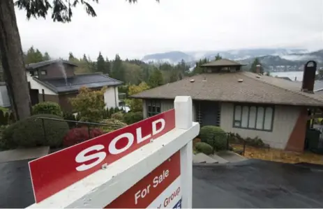  ?? JONATHAN HAYWARD/THE CANADIAN PRESS FILE PHOTO ?? A sold sign stands outside a home in North Vancouver. In Vancouver, the benchmark home price is $919,300 or $1.06 million with the tax.