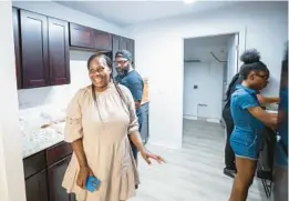  ?? WILLIE J. ALLEN JR./ORLANDO SENTINEL PHOTOS ?? TOP: Keetonia Wilson, center, shows Orange County Mayor Jerry Demings through her new Habitat for Humanity home in Apopka on Saturday. Wilson is college-educated and had been moving up the corporate ladder until an accident changed her life, and she became fully disabled in 2015. The rents in Miami were unaffordab­le; she then moved to Orlando in 2016 to be near family. Her debts and the high rent were stumbling blocks, but she had a dream and promised her children they would eventually have a home to call their own. Thanks to Habitat for Humanity, her hard work and her family’s support, the promise was delivered.
ABOVE: Wilson, center, wears a big smile as she walks through her brand new Habitat for Humanity home.