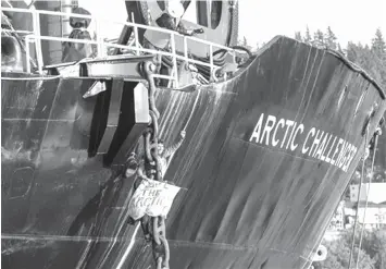  ?? ASSOCIATED PRESS ?? A woman identified as Chiara Rose suspends herself in a climbing harness from the anchor chain of the Royal Dutch Shell support ship Arctic Challenger in the harbor at Bellingham, Washington.