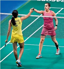  ?? AFP ?? Carolina Marin of Spain (right) shakes hands with P.V. Sindhu of India after beating her in the women’s singles quarterfin­al match of the Singapore Open badminton tournament in Singapore on Friday. Sindhu lost 11-21, 15-21. —