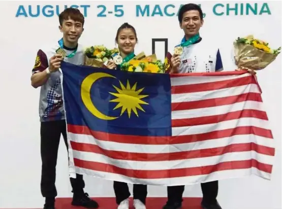  ??  ?? All for our country: Loh Choon How (right) and Khaw Jun Lim (left) raised double cheers for Malaysia with golden strikes in the World University Wushu Championsh­ip in Macau. Aggie Cheah (centre) won a silver.