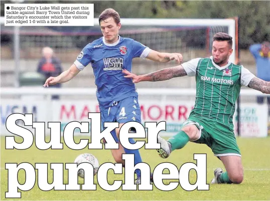  ??  ?? Bangor City’s Luke Wall gets past this tackle against Barry Town United during Saturday’s encounter which the visitors just edged 1-0 with a late goal.