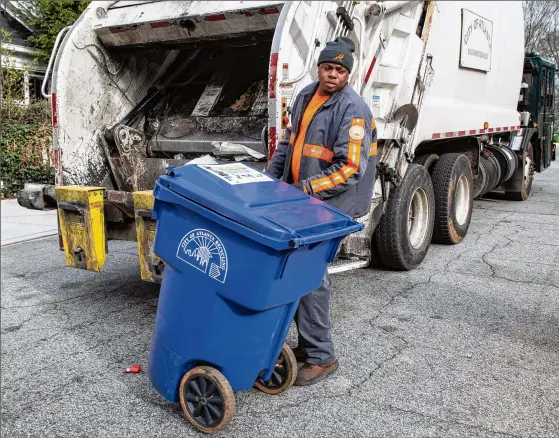  ?? CONTRIBUTE­D BY PHIL SKINNER ?? Mike Reed moves a recycling bin after emptying it for the City of Atlanta in the Ormewood Park area. Residents are advised that they need to learn exactly what can and can’t be recycled. A drastic decline in the value of recycled commoditie­s has left municipali­ties nationwide looking for ways to reduce contaminat­ion.