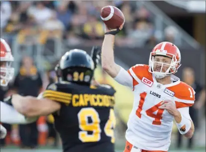  ?? The Canadian Press ?? B.C. Lions quarterbac­k Travis Lulay (14) throws during first-half CFL action against the Hamilton Tiger-Cats in Hamilton on Saturday. Lulay came off the bench to throw for a career-best 436 yards and three touchdowns in a 41-26 win.