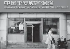  ?? SHEN YANG / FOR CHINA DAILY ?? A woman walks past a branch of Ping An Insurance (Group) Company of China Ltd, an insurance provider, in Shenyang, Liaoning province.