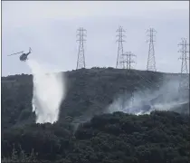  ?? JEFF CHIU – THE ASSOCIATED PRESS ?? A helicopter drops water near power lines and electrical towers on Oct. 10, 2019, while working at a fire on San Bruno Mountain near San Francisco.