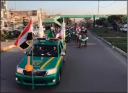  ?? AP/ALI ABDUL HASSAN ?? Iraqi security forces raise Iraqi national flags in a parade Monday marking the year anniversar­y of the defeat of the Islamic State group in Tahrir Square in central Baghdad.