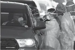  ?? JOE RAEDLE/GETTY ?? Health workers administer vaccines at a drive-thru site Wednesday at the Hard Rock Stadium.