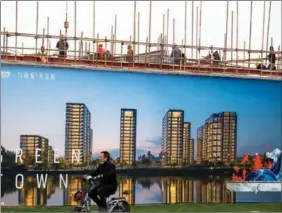  ?? XU JINBAI / FOR CHINA DAILY ?? A man cycles past a constructi­on site in Hai’an, Jiangsu province.