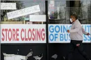  ?? NAM Y. HUH — THE ASSOCIATED PRESS FILE ?? A man looks at signs of a closed store due to COVID-19 in Niles, Ill. U.S. layoffs surged in April revealing the deep economic hole that comes with shuttered offices, restaurant­s, stores and schools.