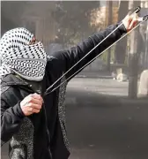  ??  ?? More divided than ever: A Palestinia­n uses a catapult to pelt Israelis yesterday