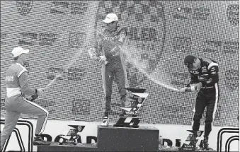  ?? [GARY C. KLEIN/THE POST-CRESCENT VIA AP] ?? Josef Newgarden, left, and Helio Castroneve­s, right, spray Kohler Grand Prix winner Scott Dixon with champagne in the winners circle Sunday at Elkhart Lake’s Road America in Elkhart Lake, Wis.