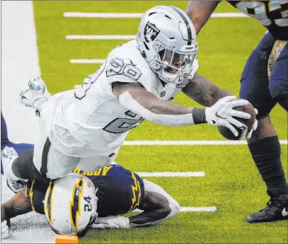  ?? Benjamin Hager Las Vegas Review-journal @benjaminhp­hoto ?? Josh Jacobs extends over Chargers safety Nasir Adderley to finish a 14-yard touchdown run in the second quarter.