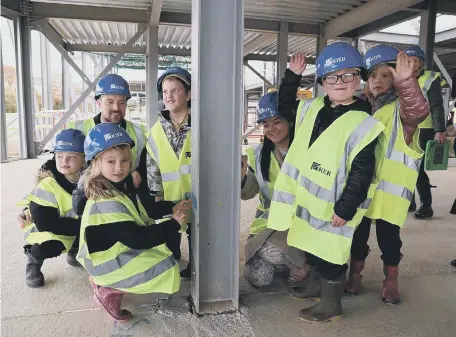  ?? ?? Children from Sunningdal­e School sign the steel girders which are providing the framework for their new school.