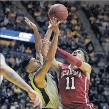  ?? [RAYMOND THOMPSON/THE ASSOCIATED PRESS] ?? Oklahoma guard Trae Young shoots while being defended by West Virginia guard James Bolden during the first half.