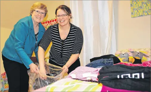  ?? MILLICENT MCKAY/JOURNAL PIONEER ?? Carolyn Francis, left, and April Ramsay, members of the Kensington and Area Refugee Sponsorshi­p Initiative, go through a bag of donated girls clothes, sorting through sizes for a member of the Syrian refugee family who is moving to Kensington.