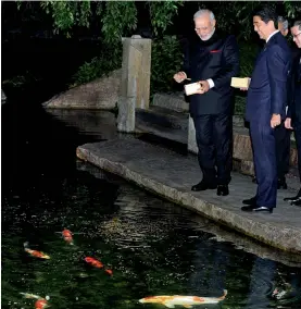  ??  ?? Prime Minister Narendra Modi and his Japanese counterpar­t, Mr Shinzo Abe, feed carp at a guesthouse in Kyoto, Japan, on Saturday. —