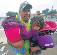  ??  ?? A man carries children after being rescued from flooding and, below, Mark Ocosta and his baby Aubrey take refuge in one of the shelters in Houston.