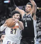  ?? Eric Gay The Associated Press ?? Denver Nuggets guard Jamal Murray drives against the San Antonio Spurs on Friday but finds imposing 7-foot-4-inch center Victory Wembanyama in the way.