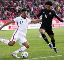  ?? NATHAN DENETTE — THE CANADIAN PRESS VIA AP, FILE ?? Canada’s Tajon Buchanan, right, pressures United States’ Miles Robinson during the first half of a World Cup soccer qualifier in Hamilton, Ontario, Jan. 30, 2022. Atlanta United defender Robinson will likely miss the World Cup for the United States after rupturing the Achilles tendon in his left leg during an MLS game.