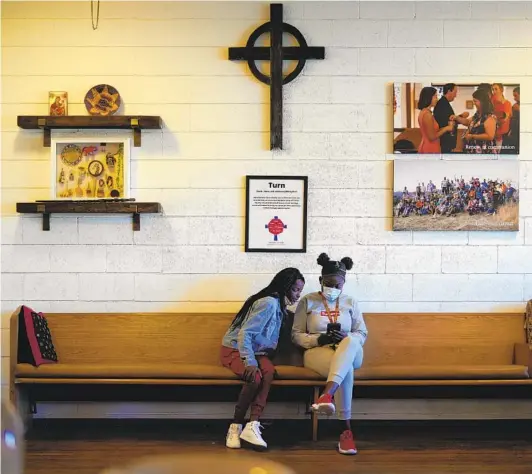  ?? NELVIN C. CEPEDA U-T ?? Martha Mulumbilwa (left) and Annet Keji look over a social media post before the start of their remote Zoom learning at St. Luke’s North Park in February. The two are among 19 school children taking advantage of the church’s learning pod program. They attend from 8 a.m. to 1 p.m. and are provided with meals.