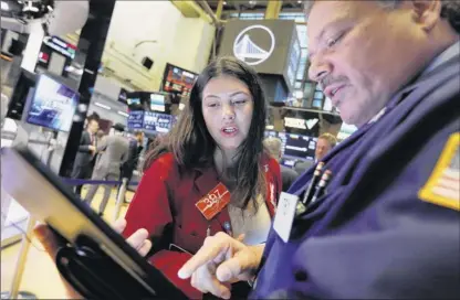  ?? Richard Drew / Associated Press ?? Traders Ashley Lara and John Santiago confer Monday on the floor of the New York Stock Exchange. Stock s opened broadly lower on Wall Street, and the market’s losing streak extended the into a fourth week.