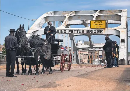 ?? GEORGE WALKER IV/ USA TODAY NETWORK ?? The casket carrying Rep. John Lewis crosses the Edmund Pettus Bridge, site of Lewis’ heroism in the civil rights movement, as crowds look on during a celebratio­n of his life Sunday in Selma, Ala.