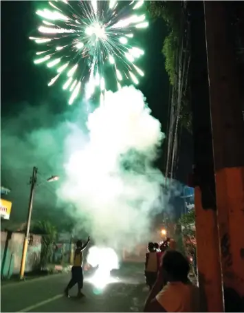  ??  ?? Some Christmas revelers in Mandaue City light up pyrotechni­cs in the middle of the road.