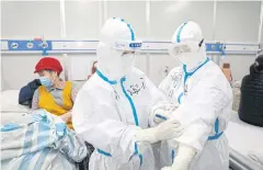  ?? REUTERS ?? A medical worker writes down a patient’s dietary informatio­n on a colleague’s protective suit inside Leishensha­n Hospital in Wuhan, China on Sunday.