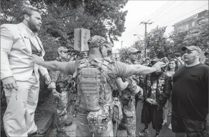  ?? Photo for The Washington Post by Evelyn Hockstein ?? A member of ‘The Militia’ keeps the peace outside the Unite the Right rally on Saturday in Charlottes­ville, Va.