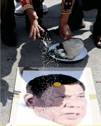  ?? AP FOTO ?? RITUAL. Protesters perform a ‘ritual’ on a photo of President Rodrigo Duterte in Manila.