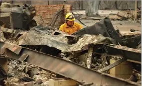  ?? AP PHOTO BY JOHN LOCHER ?? A firefighte­r looks through a home destroyed by the Camp Fire where human remains were found, Sunday, Nov. 11 in Paradise, Calif.