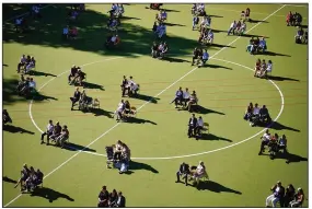  ?? (AP/dpa/Kay Nietfeld) ?? At a German high school graduation ceremony Tuesday in Berlin, graduates and their relatives sit for the ceremony in designated spaces on a playing field.