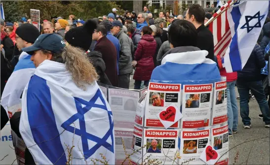  ?? CHRIS CHRISTO — BOSTON HERALD ?? People gather earlier this month to dedicate the rebuilt vandalized hostage memorial wall in front of a home on Homer Street in Newton, honoring those taken at the outset of the war in Gaza.