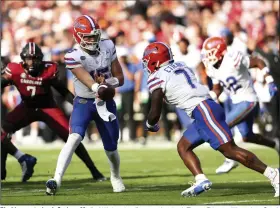  ?? (AP/Artie Walker Jr.) ?? Florida quarterbac­k Graham Mertz (15) hands off to running back Trevor Etienne (7) against South Carolina on Saturday in Columbia, S.C. Mertz threw for a career-high 423 yards and tossed three touchdowns while Etienne added 49 yards and a score on the ground in Florida’s come-from-behind 41-39 win.