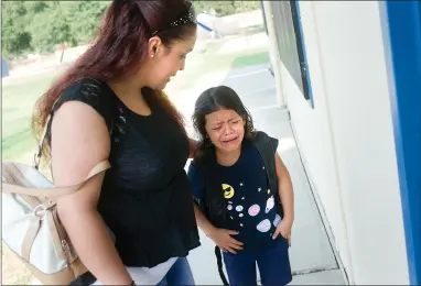  ?? RECORDER PHOTOS BY CHIEKO HARA ?? Even with encouragem­ent from mother Yesenia Ceballos, left, Genesis Ceballos, 7, is less than excited to enter her new classroom and begin the school year Thursday, Aug. 9, at West Putnam Elementary School. Thousands of Portervill­e students headed back to class Thursday morning to begin the 2018-19 school year.