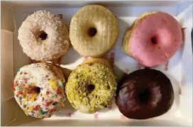  ?? WENDELL BROCK FOR THE AJC ?? A box of doughnuts from Hero Doughnuts & Buns includes (top row) coconut, original glazed, strawberry glazed, (bottom row) cereal milk, pistachio and chocolate glazed.
