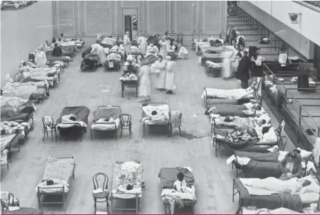  ?? [PHOTO BY EDWARD A. “DOC” ROGERS, LIBRARY OF CONGRESS/AP] ?? BELOW: In this 1918 photo made available by the Library of Congress, volunteer nurses from the American Red Cross tend to influenza patients in the Oakland Municipal Auditorium, used as a temporary hospital.