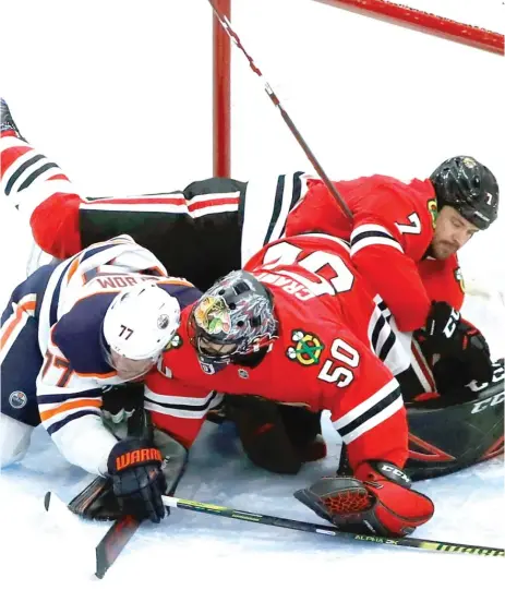  ?? CHARLES REX ARBOGAST/AP ?? Oilers defenseman Oscar Klefbom and Blackhawks defenseman Brent Seabrook land on goalie Corey Crawford in the first period.