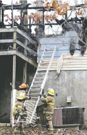  ?? STAFF PHOTO BY C.B. SCHMELTER ?? Firefighte­rs work to remove a ladder from the back of a home in the 4000 block of Shady Oak Drive on Wednesday in Ooltewah. A fire left one dead and a family displaced.