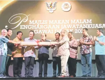  ?? ?? Sikie (front right) passes the ‘tikar lampit’ to Sagah (fourth left) to symbolise the handover of organising duties to the Bidayuh community. From left are Peter, Ik Pahon, Dr Jerip, Uggah, Dr Rundi, Mancha, Gira, and Sirai.