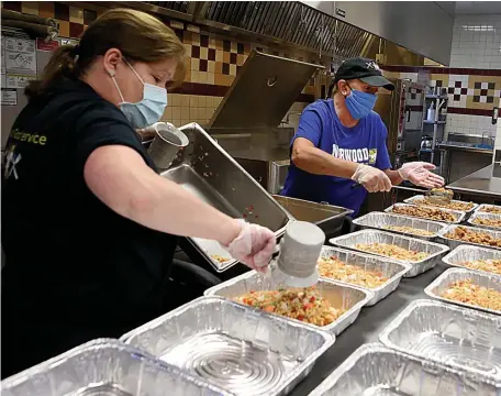  ?? NANCY LANE / HERALD STAFF ?? NO MORE SHAME: Maureen Giammarco and Gerrianne Hernon from Norwood Public Schools prepare family meals during a program in the high school cafeteria on May 19.