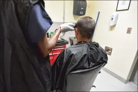  ??  ?? A detainee gets a haircut from another recently at Folkston ICE Processing Center. On the day of the AJC’s visit, the 780-bed center was holding 661 detainees.