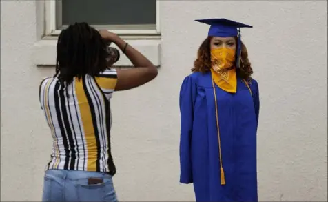  ?? Eric Gay/Associated Press ?? Anderson High School senior Teyaja Jones poses in her cap and gown — and bandanna face cover — Tuesday in Austin, Texas.