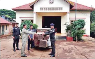  ?? PHOTO SUPPLIED ?? Military police hand over a suspected timber transporte­r and a load of luxury timber to Forestry Administra­tion officials in Kratie province.