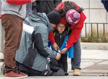  ?? ASHLEE REZIN/SUN-TIMES ?? A child gets zipped up in a winter coat outside Chicago’s designated landing zone for new migrant arrivals at 800 S. Desplaines St. in the West Loop.